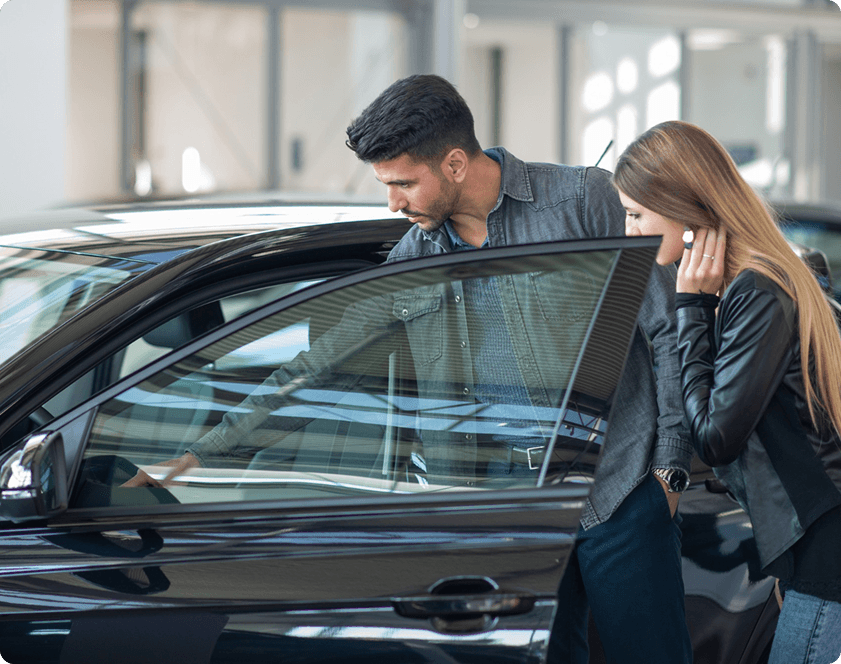 Paar inspiziert Auto im Showroom