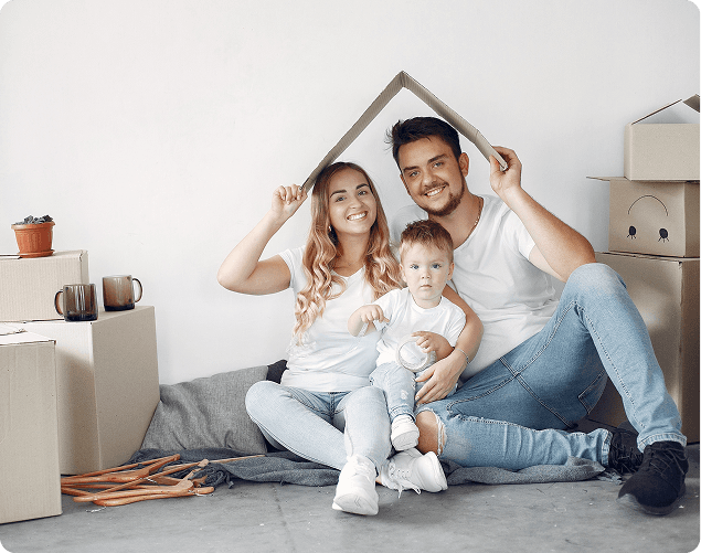 Familie sitzt mit Papphaus und Umzugskartons